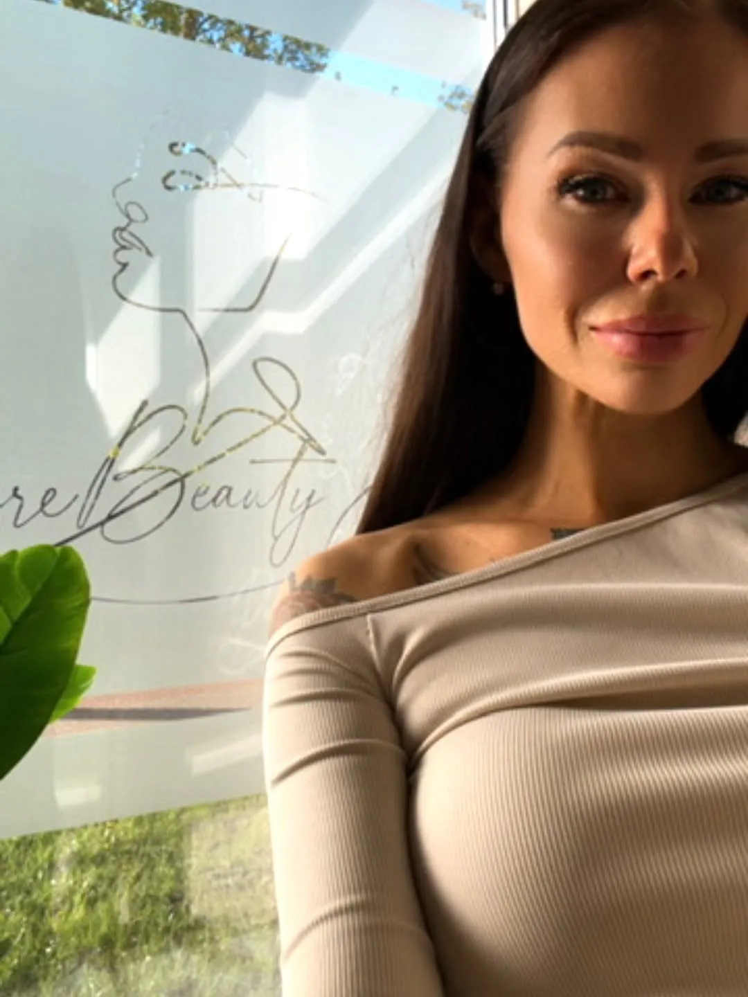 Sieviete pie loga ar zelta Pure Beauty logo uz stikla
